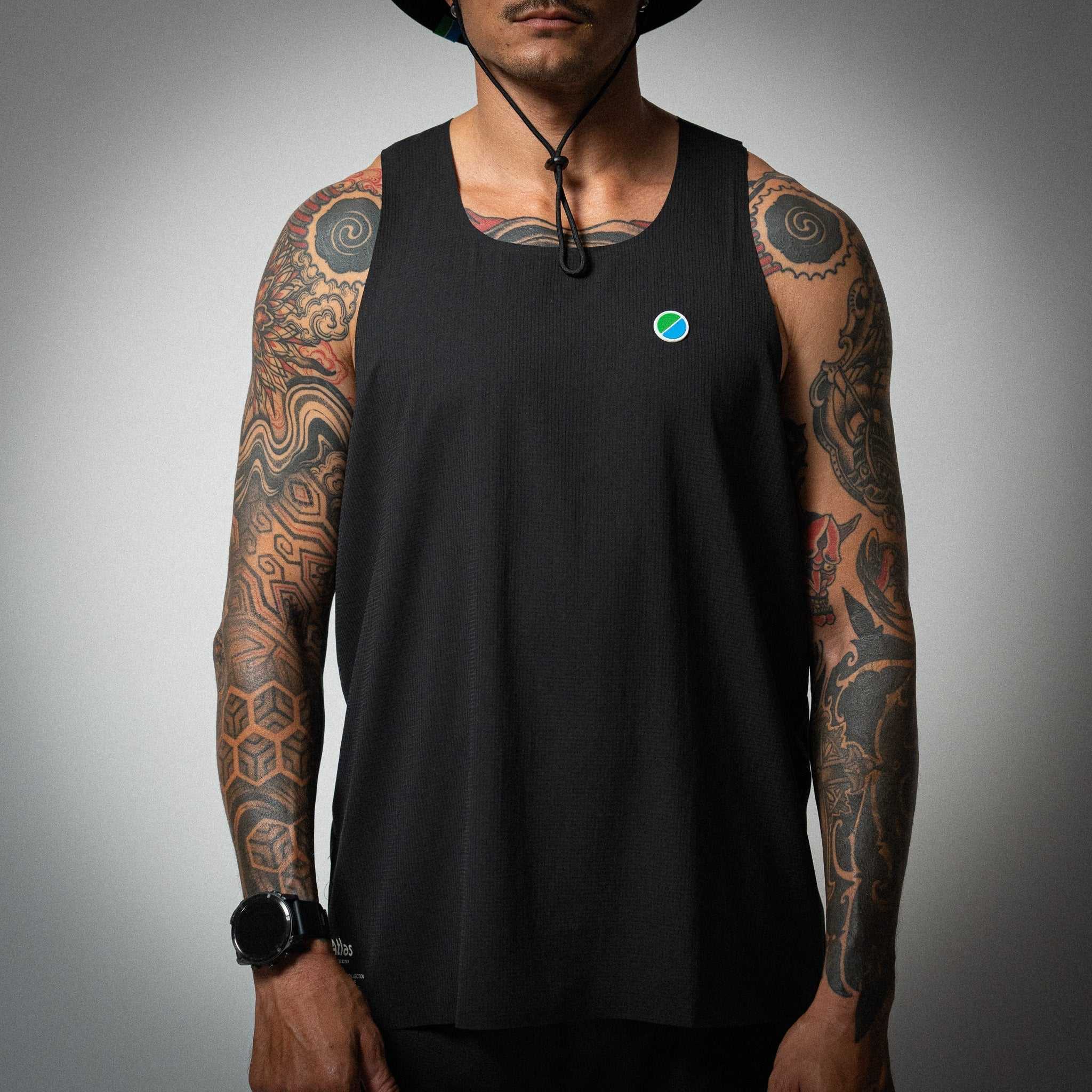 Aeria Fortis Race Tank in black worn by a model, showcasing breathable recycled ripstop fabric with silicone chest patch for runners.